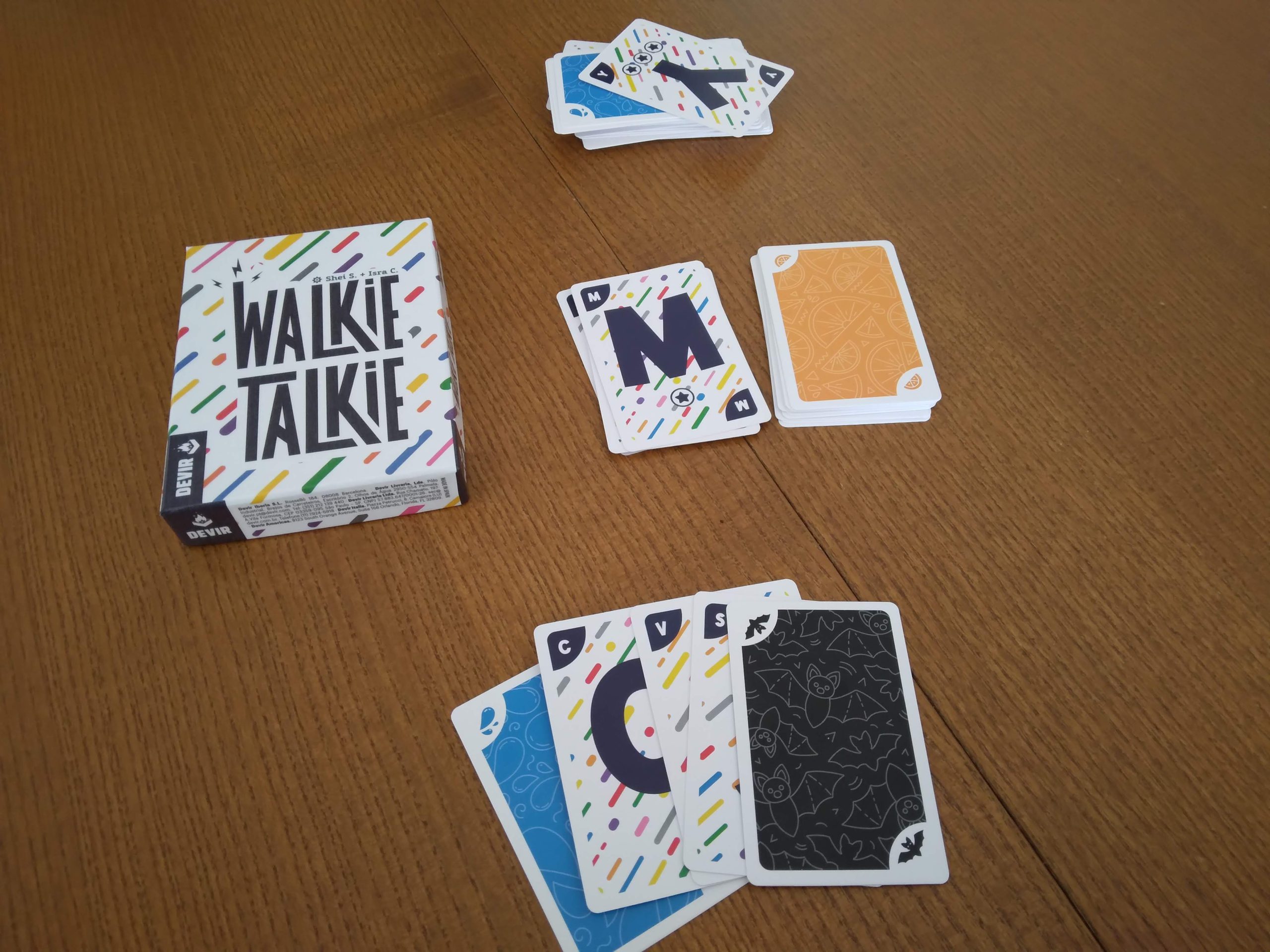 Colocación en mesa de las cartas del juego Walkie Talkie, que por una cara son letras y por la otra cara, color.